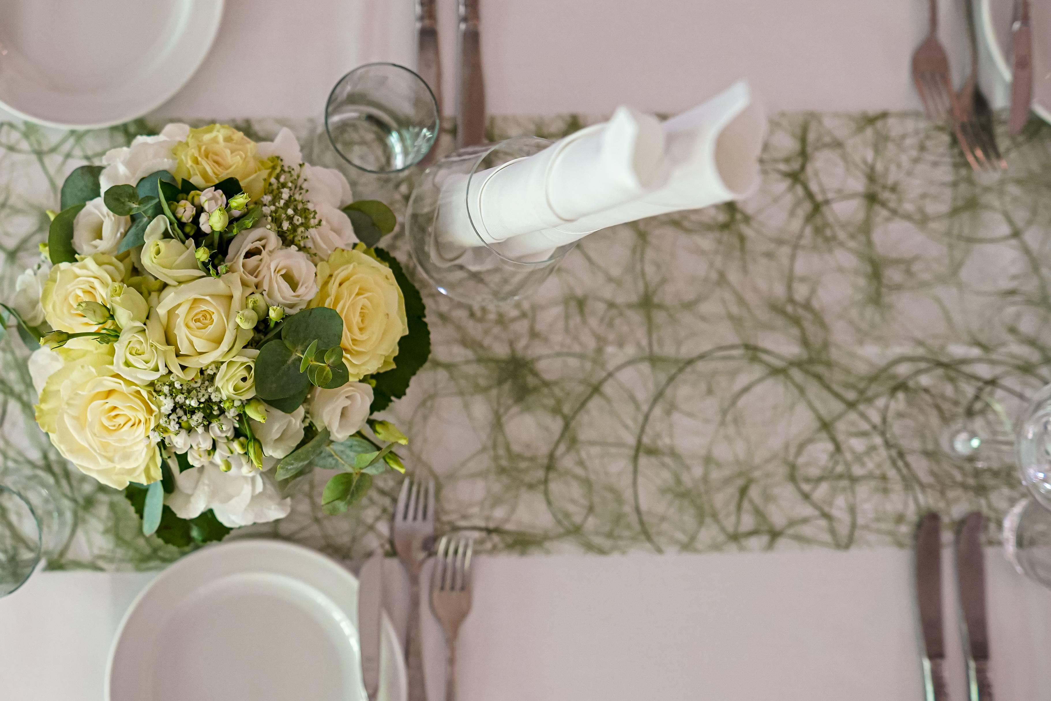 Hochzeitstisch mit Blumenstrauß und grüner Tischdecke