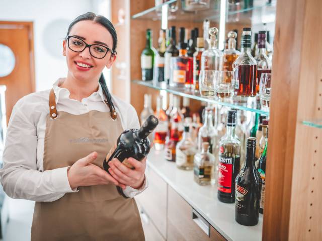 Hotelmitarbeiterin an der Hotelbar hält Flasche in der Hand